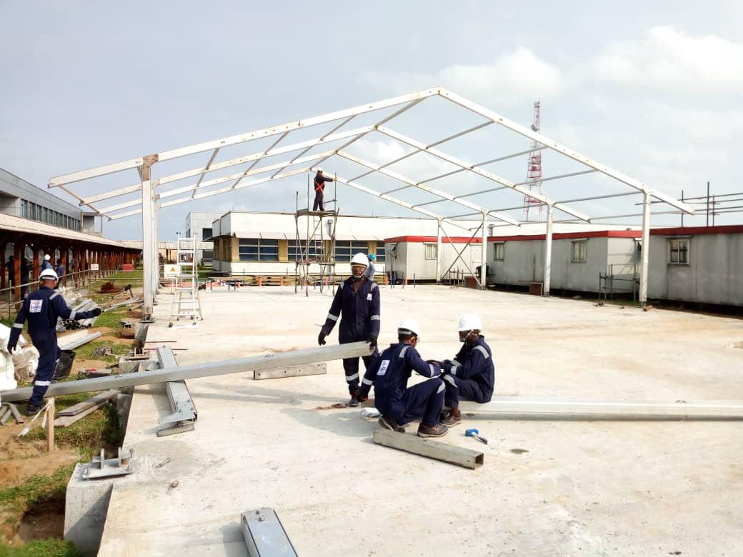 Workers with PPE installing tent
